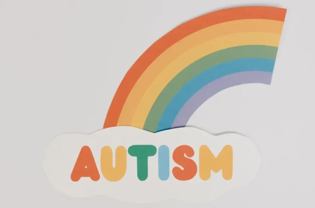 Rainbow with autism written below with each letter with a different color matching the rainbow above